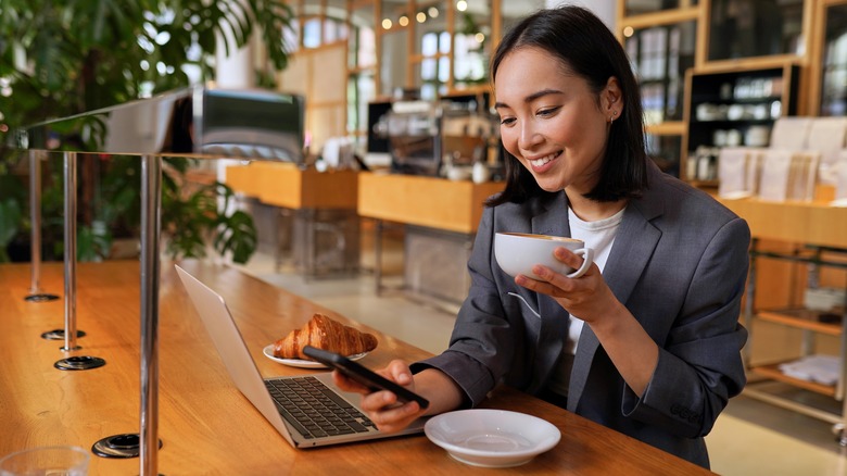 Woman at cafe smiling at text 