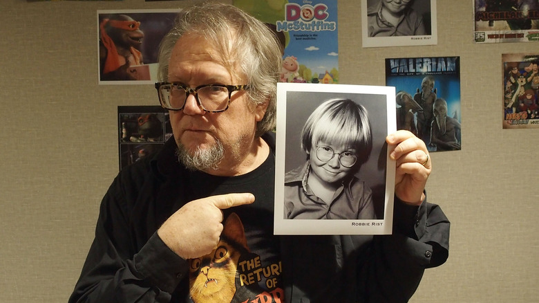 Robbie Rist pointing at a photo of his younger self
