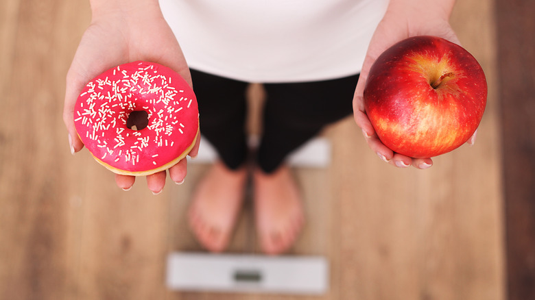 Woman weighing donut vs. apple