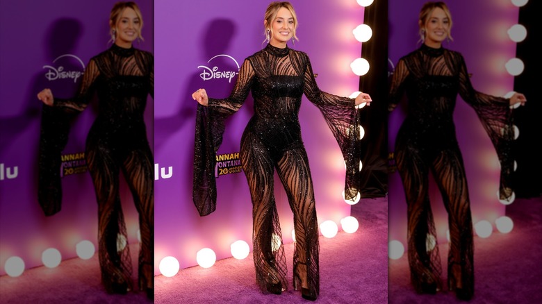 Lainey Wilson posing in a semi-sheer black jumpsuit.