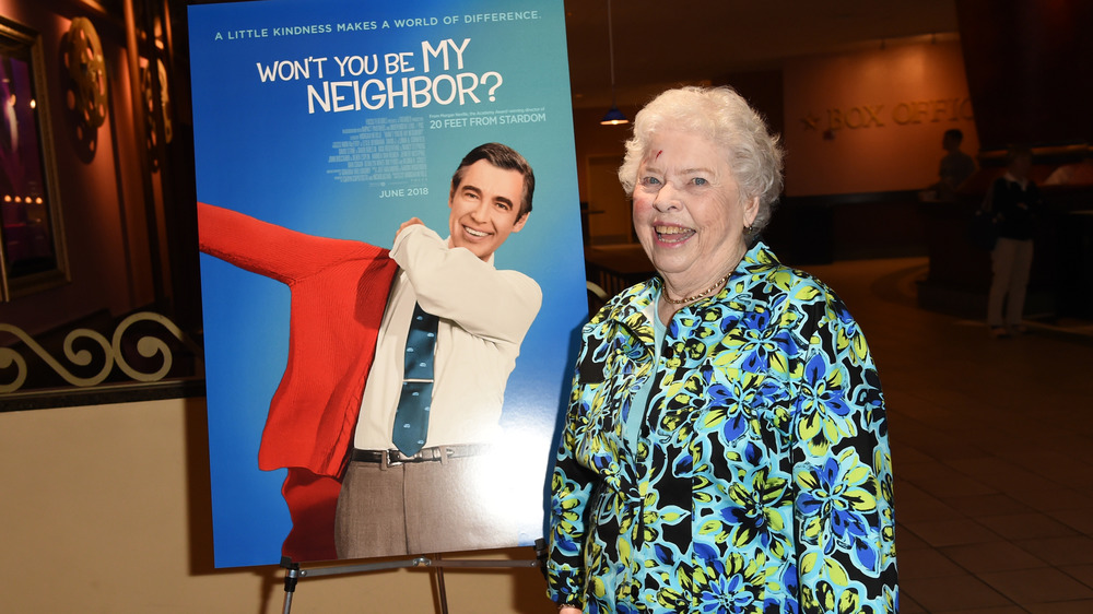 Mrs Joanne Rogers next to a "Won't You Be My Neighbor" poster