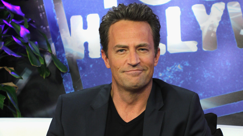 Matthew Perry in black, smirky-smiling