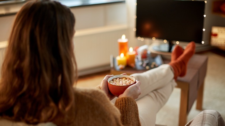 woman with hot chocolate watching tv