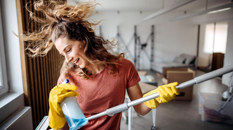 Happy woman cleaning the house while dancing