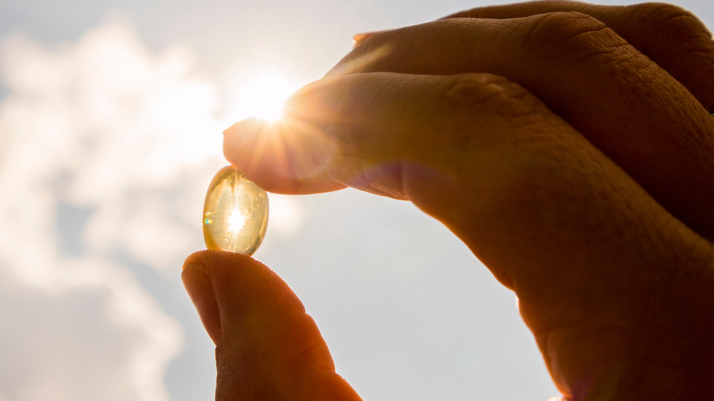 A Vitamin D pill being held up to the sun 