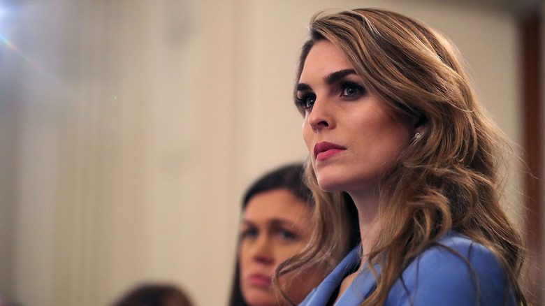 Hope Hicks looks attentively ahead at a speaker with side swept hair and a blue blazer