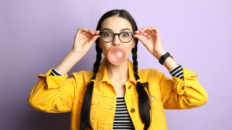 young woman with braids blowing bubblegum 