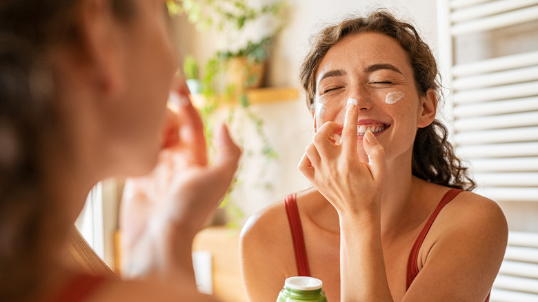 Woman applying moisturizer to face