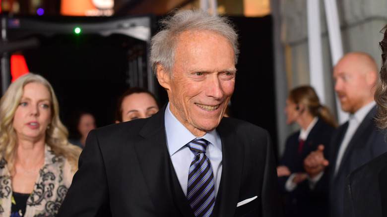 Clint Eastwood smiling at an event in 2019 wearing a black tux and blue striped tie