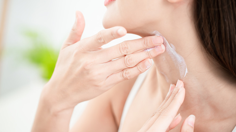 Woman applying sunscreen to her neck