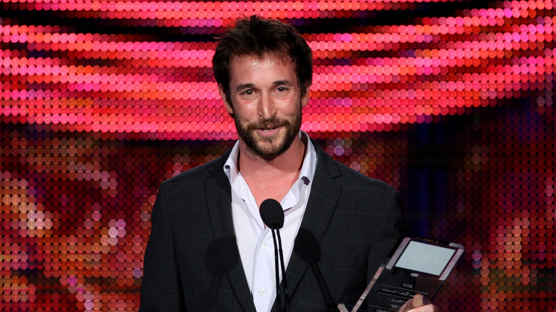 Noah Wyle speaking at a microphone and holding an award in 2010
