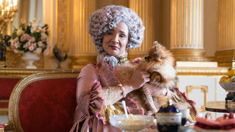 Queen Charlotte from Bridgerton holds her dog in a grey wig