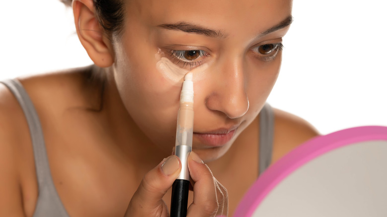 woman applying concealer under eye