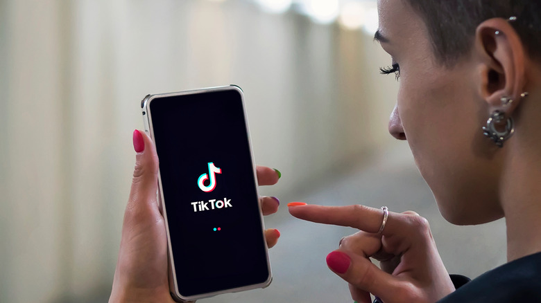 Woman holding phone with TikTok logo