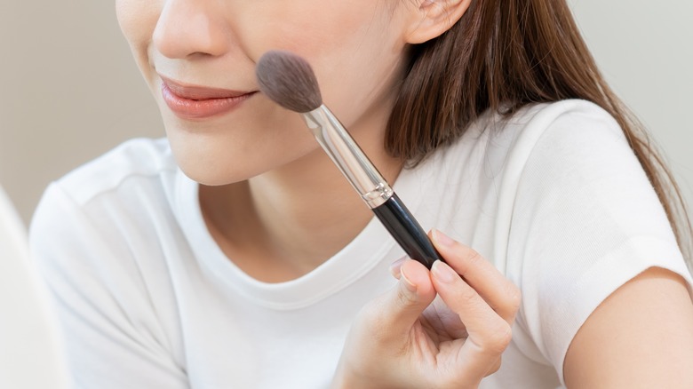 Woman applying blush with brush