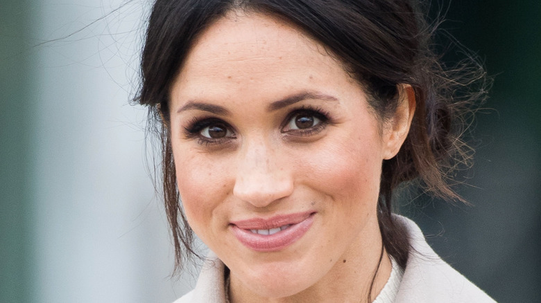 Meghan Markle smiles with her hair pulled back