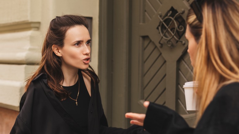 two young women arguing outside door