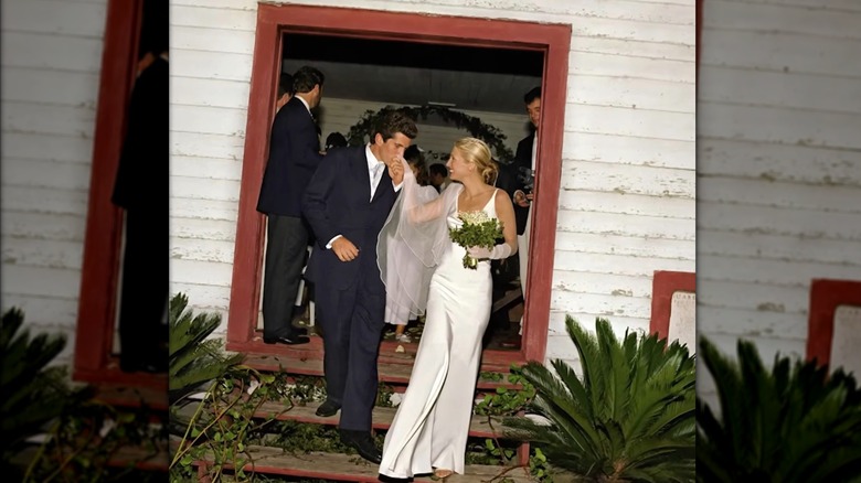 (l-r): John F. Kennedy, Jr. and Carolyn Bessette Kennedy smiling as he kisses her hand on their wedding day.