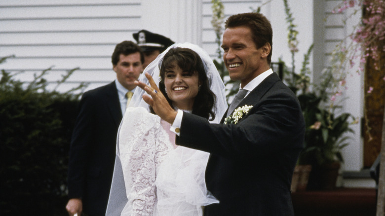 (l-r): Maria Shriver and Arnold Schwarzenegger posing and smiling outside