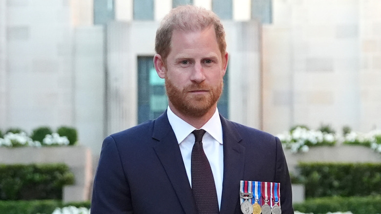 Prince Harry wearing military medals and looking solemn