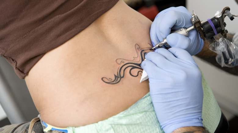 artist tattooing lower back tattoo