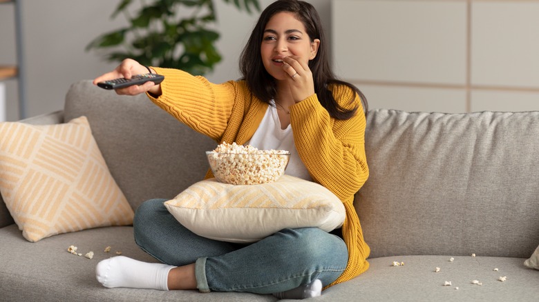 woman eating popcorn, holding remote