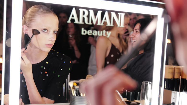 Kai Schreiber applying makeup in a mirror