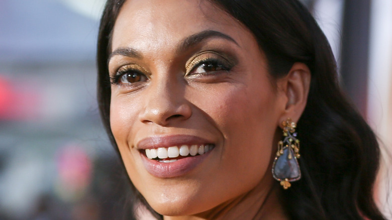 Rosario Dawson smiling as she looks over her shoulder