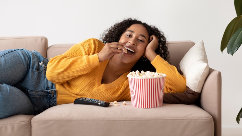 woman eating popcorn on couch