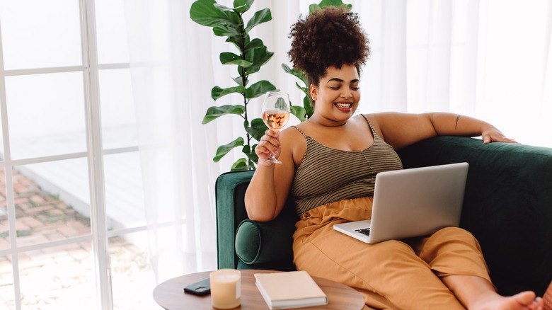 Woman drinking wine with laptop