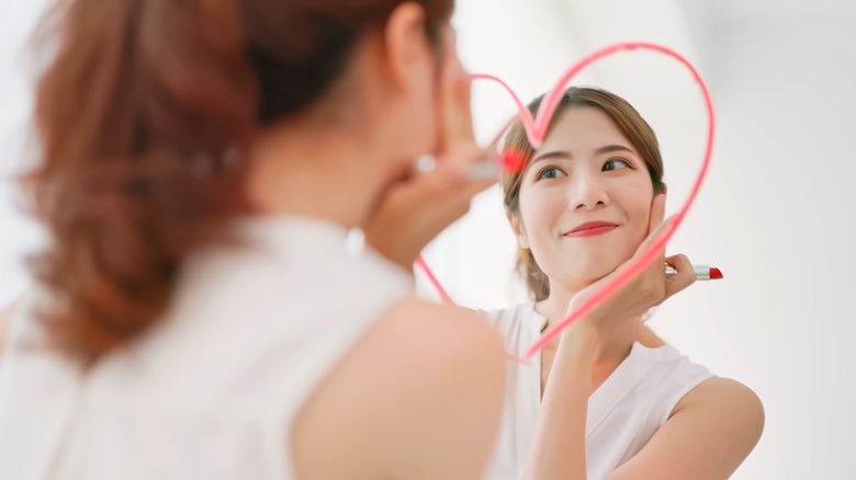 Woman draws heart on mirror with lipstick 