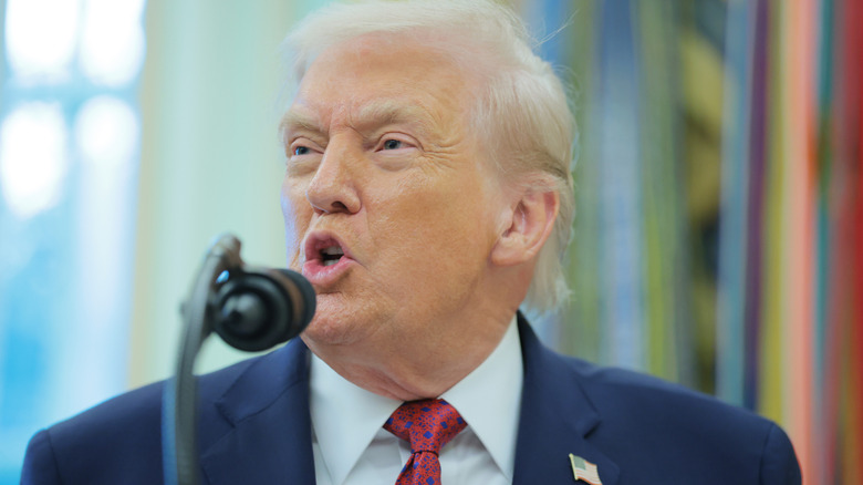 Donald Trump looking angry as he speaks over a microphone