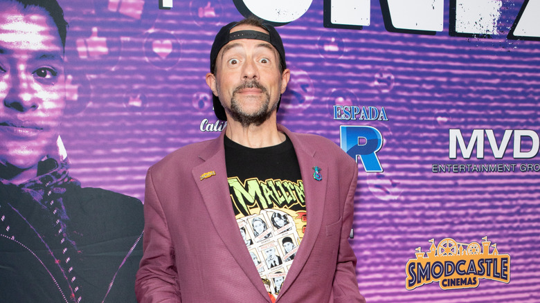 Kevin Smith posing in front of a purple background