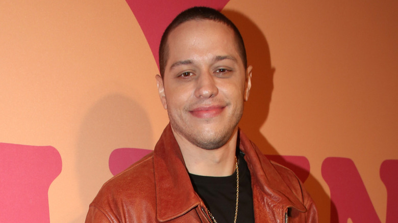 Pete Davidson in front of a peach-colored background