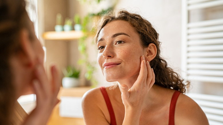 Woman looking at skin in mirror