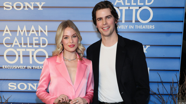 Elle Chapman wearing a pink blazer and posing next to Patrick Luwis, who wears a white T-shirt and black jacket