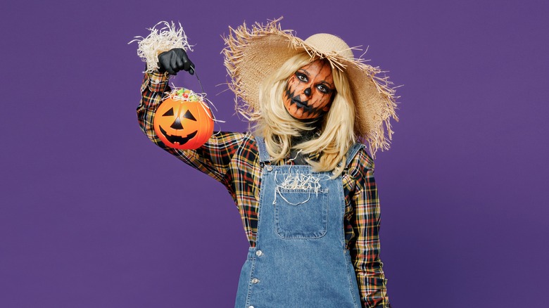 Woman in scarecrow costume with pumpkin makeup