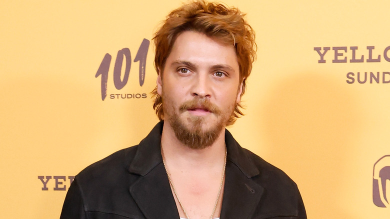 Luke Grimes in front of yellow backdrop