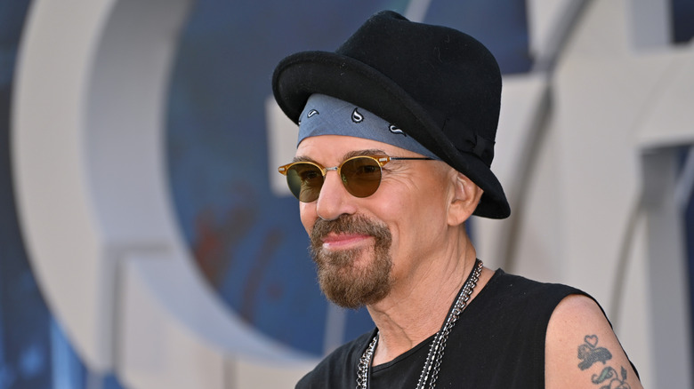 Billy Bob Thornton smiling while posing at an event in a black hat and sunglasses