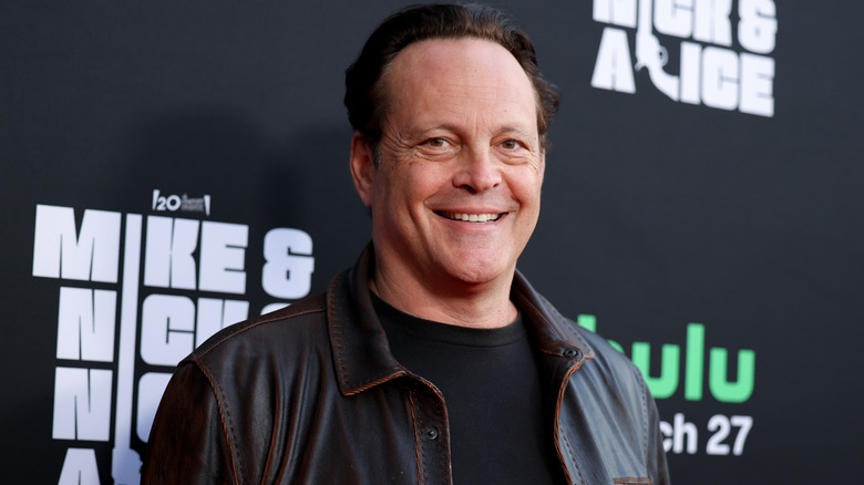 Vince Vaughn smiling in a black T-shirt and dark leather jacket.