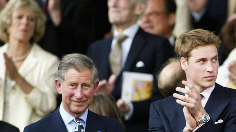 Queen Camilla standing behind King Charles and Prince William