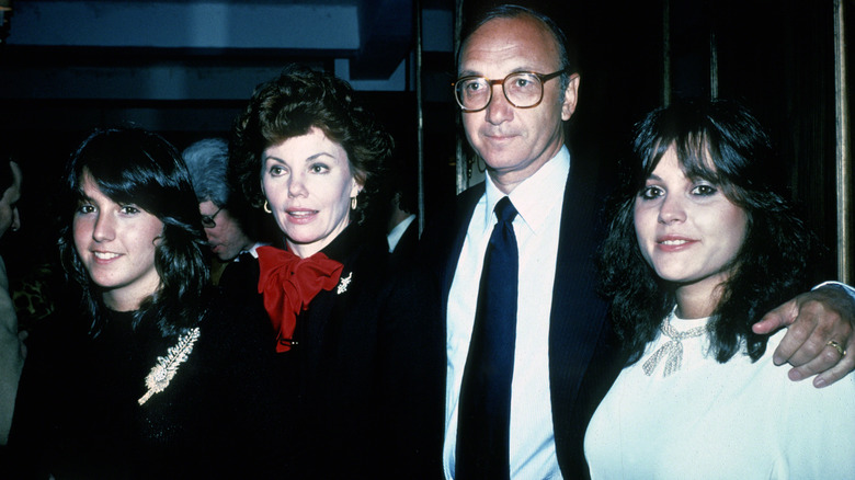 Actor Marsha Mason looks off camera and stands in between her two stepdaughters and husband Neil Simon