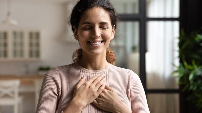 Woman smiling hands over heart