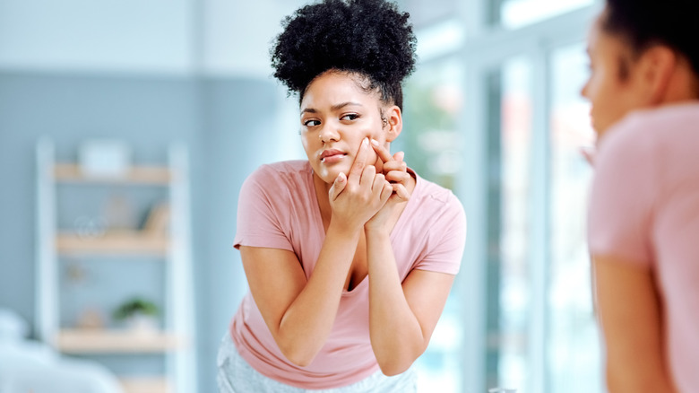 Woman squeezing a pimple on her face