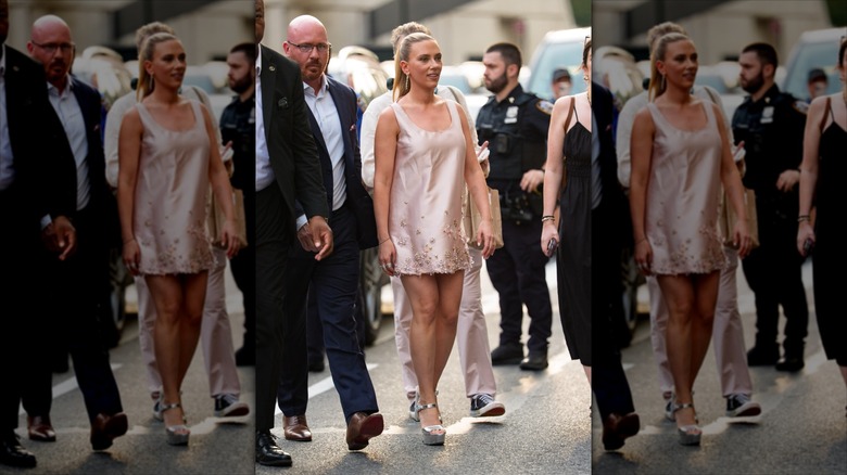 Scarlett Johansson in a mini dress, surrounded by security.