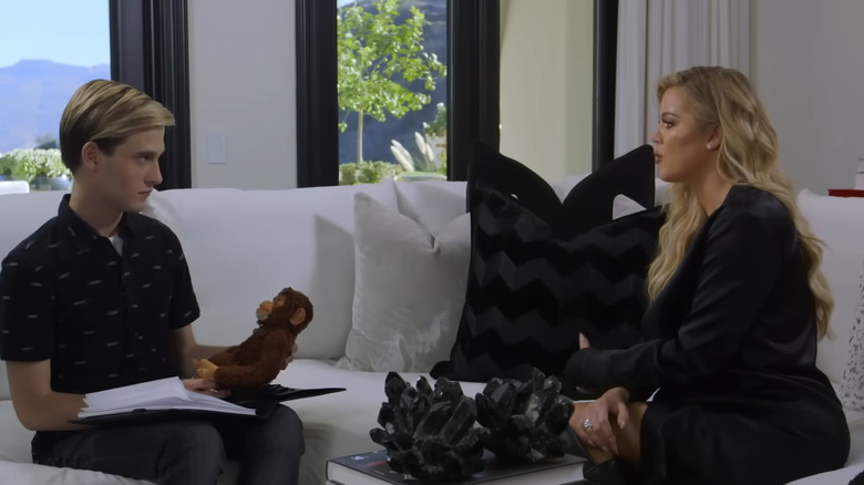 Tyler Henry and Khloé Kardashian talking on a white couch