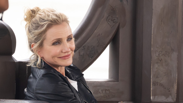 Cameron Diaz on-set in a black leather jacket and hair in a bun.