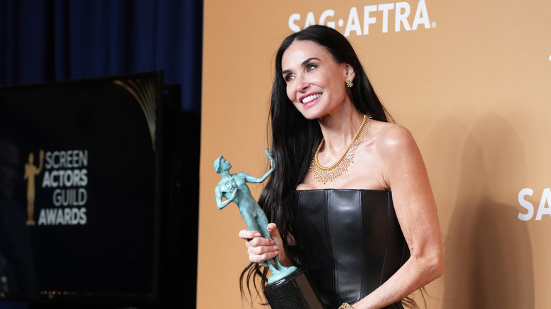 Demi Moore holding a trophy at the SAG Awards in a strapless black gown.