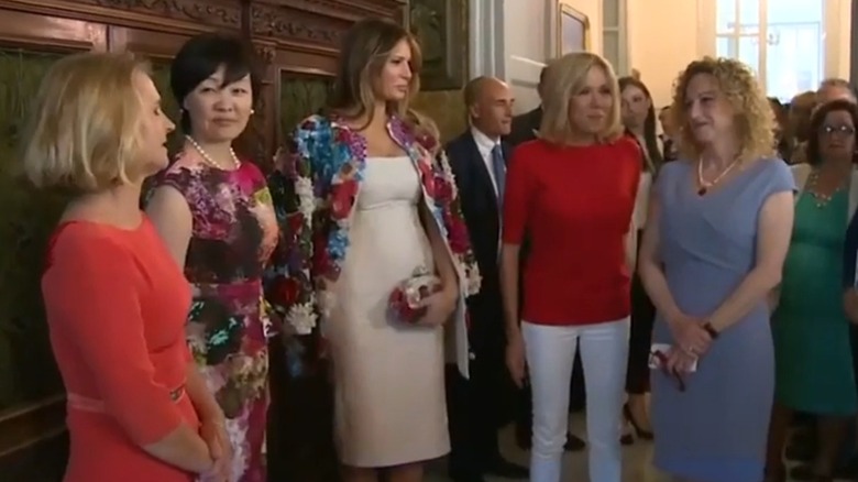 Melania Trump wearing a floral coat and posing with the spouses of world leaders in Sicily