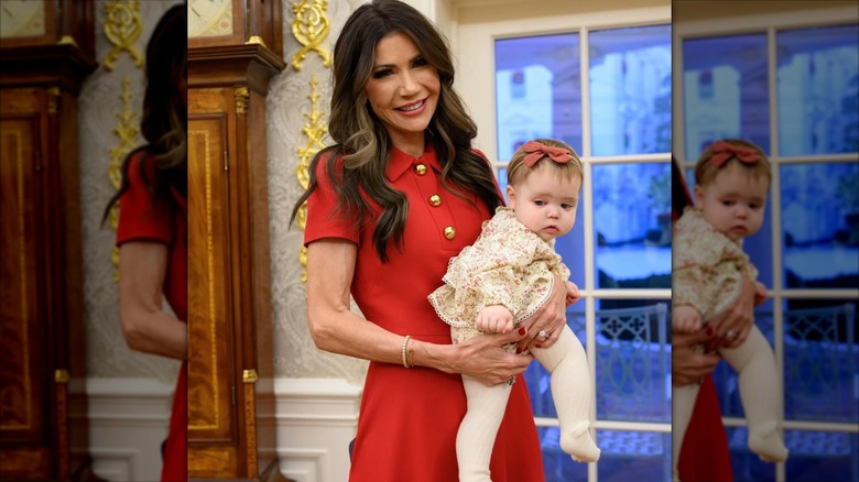Secretary of the Department of Homeland Security Kristi Noem poses while awkwardly holding a baby